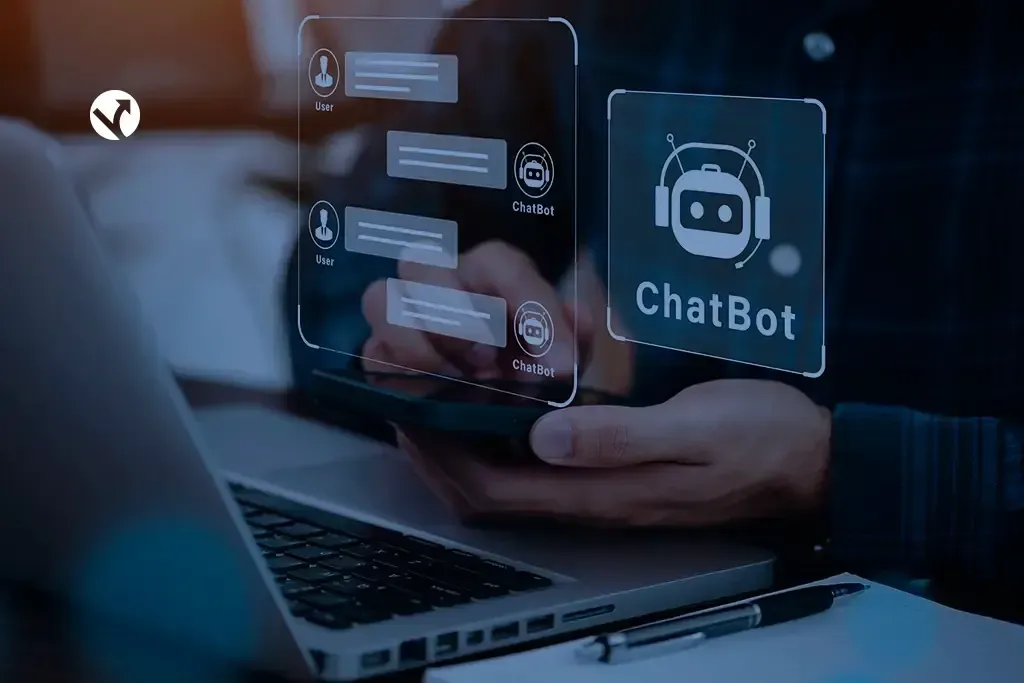Mãos segurando um celular com balões de conversa de um chatbot projetados ao lado de um notebook.